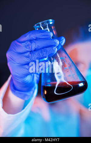Scientist working with chemicals in laboratory, female researcher analyzing liquid reagent in lab glassware Stock Photo
