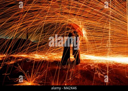 Couple under an umbrella to shelter from a shower of incandescent sparks created by the technique of steel wool, emilia romagna, italy Stock Photo