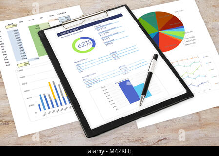 Composite image of business analytics in the office - pen and clipboard with printouts of digital data and charts on the desk. Stock Photo