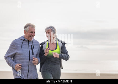 Senior couple jogging on beach Stock Photo
