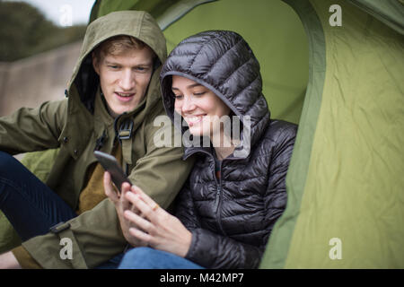 Young couple using a smartphone on a camping trip Stock Photo
