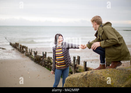 Boyfriend helping girlfriend climb a rock Stock Photo