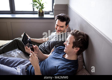 Young male couple using smartphone and digital tablet Stock Photo