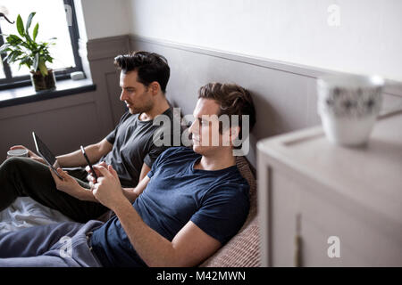 Young male couple using smartphone and digital tablet Stock Photo