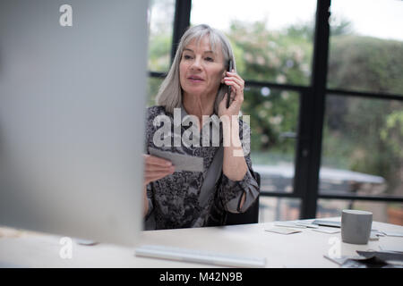 Senior businesswoman working in office using smartphone Stock Photo