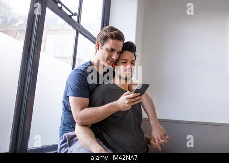 Young male couple looking at smartphone together Stock Photo