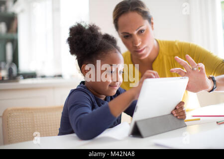 Mother teaching Daughter how to use digital tablet Stock Photo