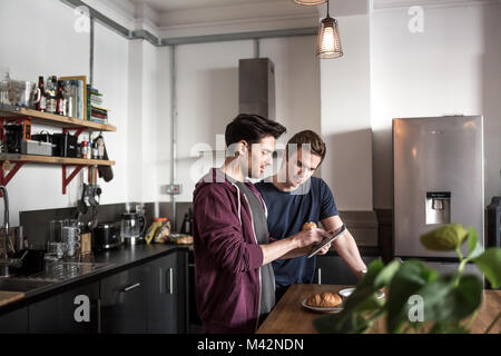 Young male couple looking at digital tablet in kitchen Stock Photo