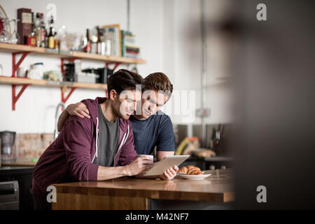 Young male couple looking at digital tablet in kitchen Stock Photo