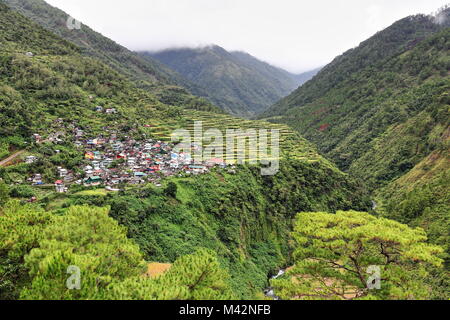 Village and rice terraces perched on the cliff over Talubin river valley in Bay-yo barangay along the road from Banaue. Bontoc municipality-Mountain p Stock Photo