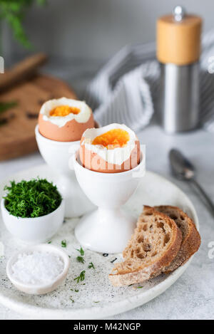 Soft boiled eggs and toasts for breakfast served with sea salt and chopped dill. Selective focus Stock Photo