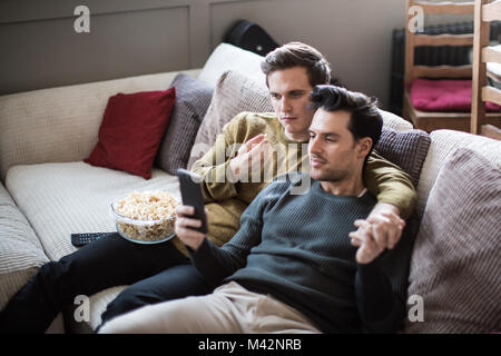 Young male couple relaxing on sofa streaming entertainment Stock Photo