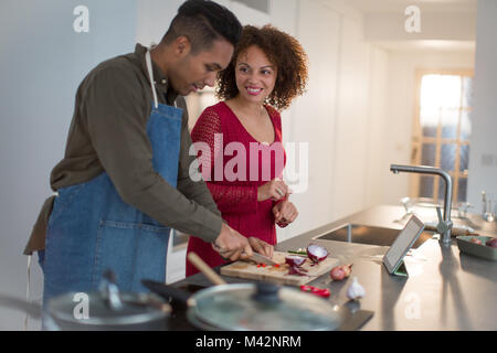 Adult male preparing dinner for girlfriend using digital tablet Stock Photo