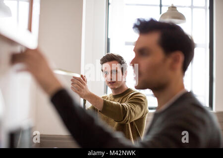 Young male couple measuring wall Stock Photo