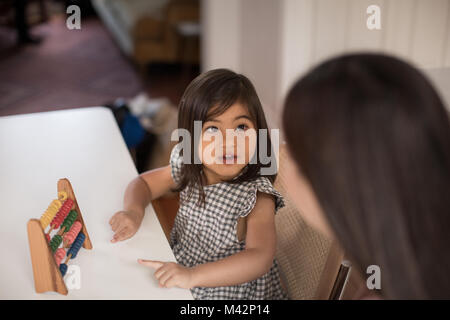 Girl using abacus to count with Mother Stock Photo