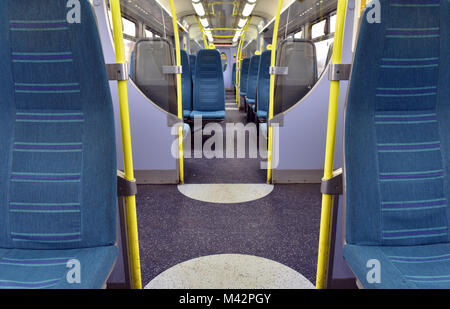 the inside of a railway carriage with blue seats in rows or lines and empty. commuting on the railways and travelling on trains and public transport. Stock Photo