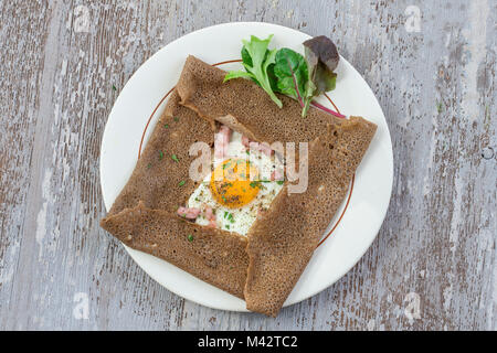 french Buckwheat crepe galette with ham and egg for tasty healthy lunch on grey wooden background Stock Photo