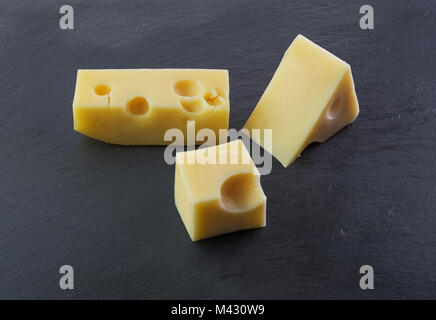 Three pieces of cheese on a black stone slate plate