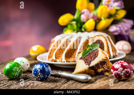 Easter Cake. Traditional ring marble cake withe easter decotation. Easter eggs and spring tulips. Stock Photo