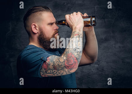 The bearded man looking through beer bottle. Stock Photo