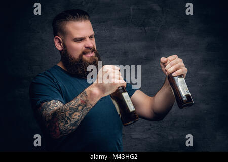 Bearded male looking at two empty beer bottles. Stock Photo