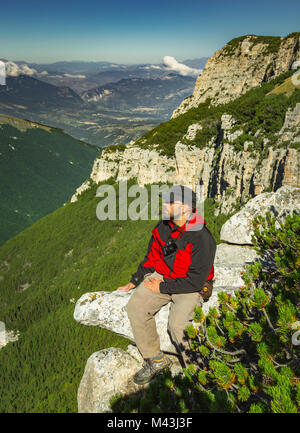 young man waiting for the good light to take a picture sitting on a rock spike with camera. Majella National Park.  Abruzzo, Italy, Europe Stock Photo