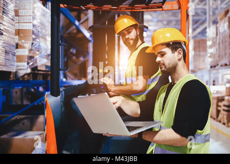 Warehouse workers working together with forklift loader Stock Photo