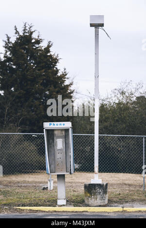 Abandoned payphone box next to a lamp post. Phone is missing. Stock Photo