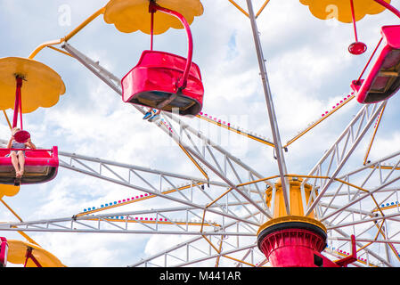 Colorful roller coaster seats at amusement park. People having fun in carousel. Wheel is spinning fast. Stock Photo