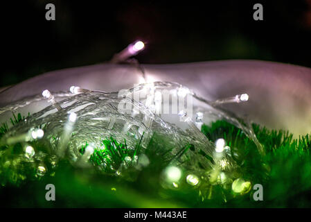 Abstract, blurry, vibrant and colorful background. A shot of Christmas lights lit on a table next to a Christmas Tree Stock Photo