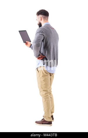 Back view of stylish modern businessman holding tablet with hand on hip. Full body length portrait isolated on white studio background. Stock Photo