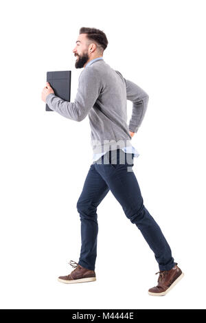 Profile view of young businessman with notebook running. Deadline concept. Full body length portrait isolated on white studio background. Stock Photo