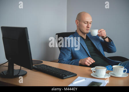 Businessman drinking coffee in office Stock Photo