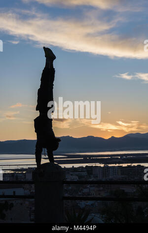 Silhouette of man doing handstand on railing, Cagliari, Sardinia, Italy