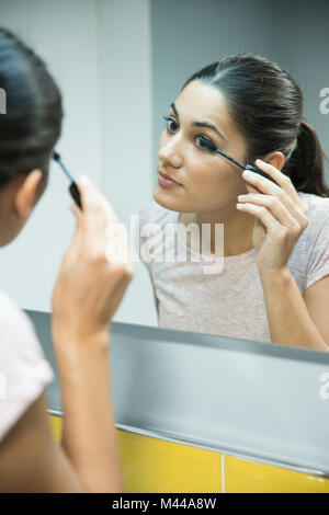 Woman applying mascara in front of mirror Stock Photo