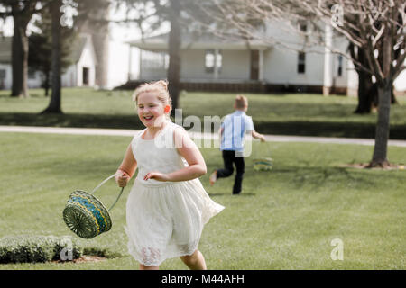 Girl and boy outdoors, holding Easter baskets, on Easter egg hunt Stock Photo