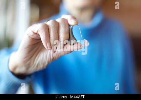 Senior woman holding hearing aid, close-up Stock Photo