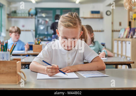 Schoolgirl writing in classroom lesson in primary school Stock Photo