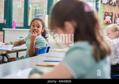 Schoolgirl looking over her shoulder in classroom at primary school Stock Photo