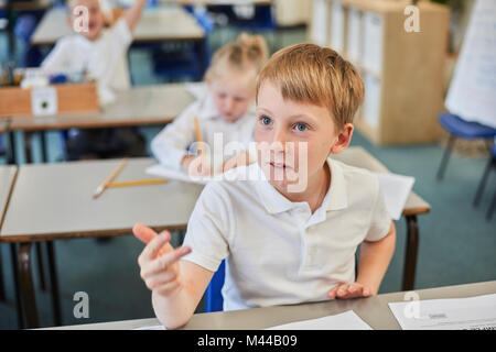 Schoolboy counting with fingers in classroom at primary school Stock Photo