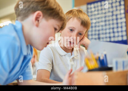 Two schoolboys problem solving in classroom at primary school Stock Photo
