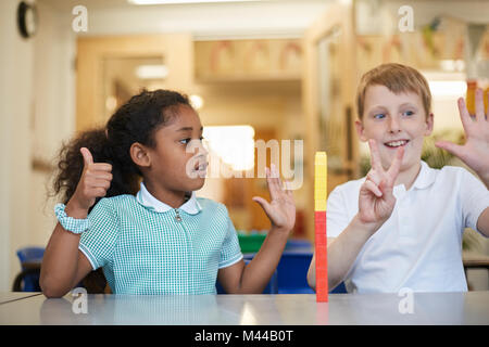 Schoolboy and girl counting on fingers in classroom at primary school Stock Photo