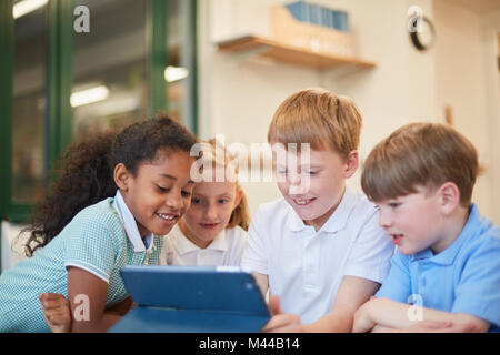 Schoolboys and girls looking at digital tablet in classroom at primary school Stock Photo