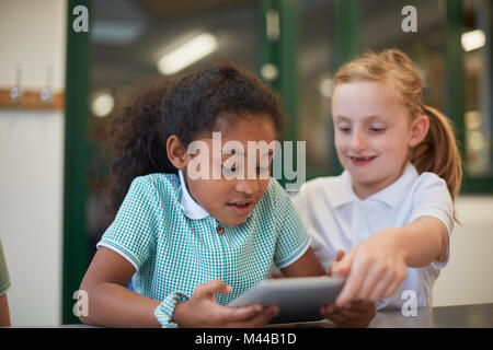Two schoolgirls looking at digital tablet in classroom at primary school Stock Photo