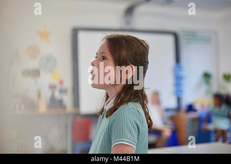 Schoolgirl answering in class at primary school Stock Photo
