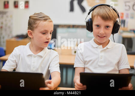 Schoolboy listening to headphones in class at primary school, portrait Stock Photo