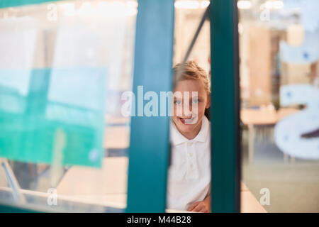 Portrait of schoolgirl looking through classroom window at primary school Stock Photo