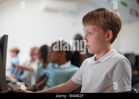 Schoolboy using computer in classroom at primary school Stock Photo