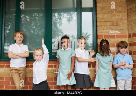 Schoolgirls and boys standing outside primary school building Stock Photo