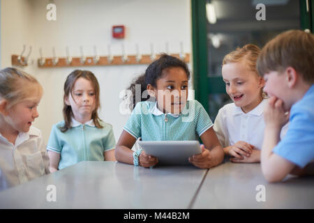 Schoolgirls and boy using digital tablet in classroom lesson at primary school Stock Photo